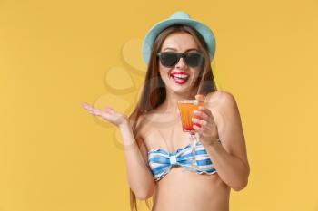 Beautiful woman in swimming suit and with tasty summer cocktail on color background�