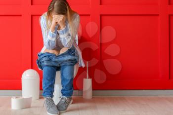Young woman suffering from hemorrhoids in restroom�