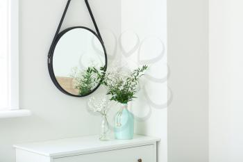 Vases with flowers and mirror in modern room�