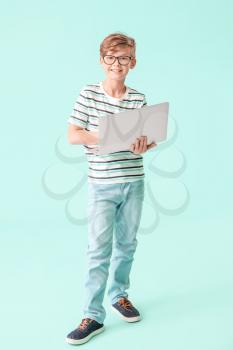Cute little boy with laptop on color background. Concept of online education�