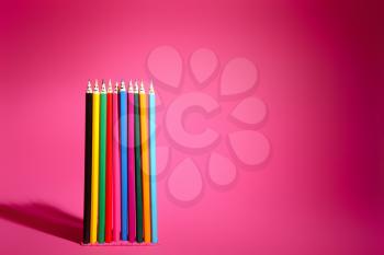 Colorful pencils with drawn faces on pink background. Unity concept�
