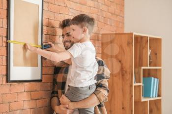 Father and son with taking measures of frame at home�