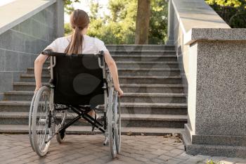 Young woman in wheelchair near stairs outdoors�