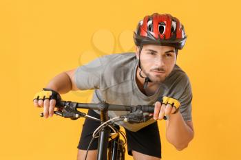 Male cyclist riding bicycle on color background�