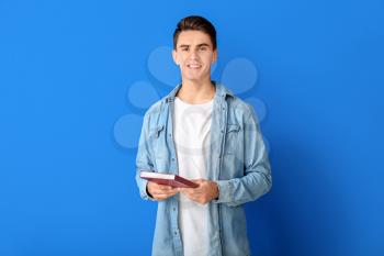 Young man with book on color background�