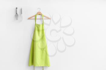 Clean apron and kitchen utensils on light background�