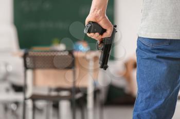 Male terrorist with gun in classroom. Problem of shooting at school�