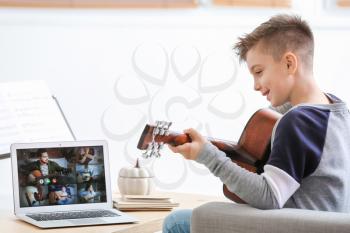 Little boy taking music lessons online at home�