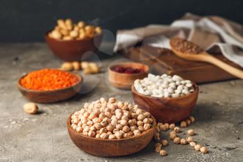 Bowls with different legumes on grey background�