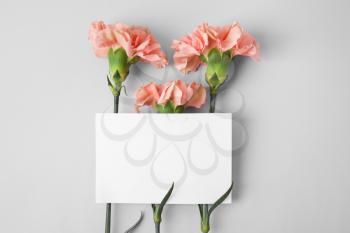 Fresh carnation flowers with empty paper sheet on grey background�