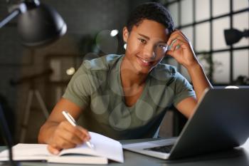 African-American student preparing for exam at home late in evening�