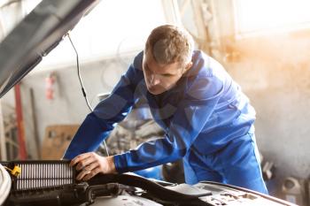 Male mechanic examining car in service center�