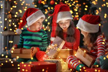 Cute little children opening magic Christmas gift at home�