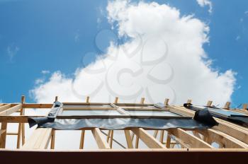 Fragment of a new residential construction home framing against a blue sky.