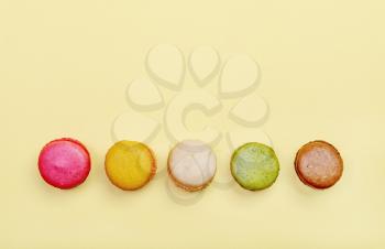 Colorful and tasty  French Macarons on yellow background.Top view.