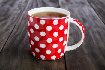 
Polka dots red cup of tea  on vintage wooden  background