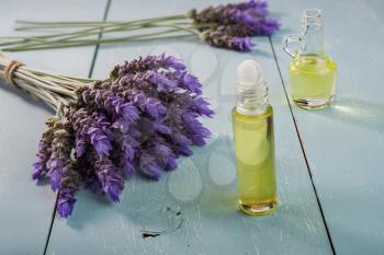 bundle of lavender flowers and essential oil  on vintage wooden background 
