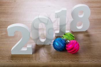 White digits 2018 with  Christmas balls on rustic  wooden background as concept of New Year and Christmas.