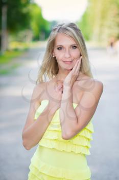 Portrait of pretty woman in yellow dress posing outdoors