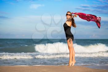 Elegant slim woman with pink pareo posing on the beach