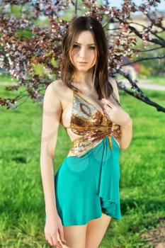 Alluring lady wearing golden and turquoise dress posing in the garden