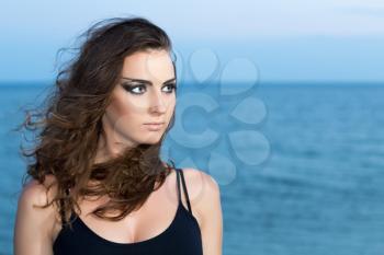 Portrait of pretty curly woman posing near the sea