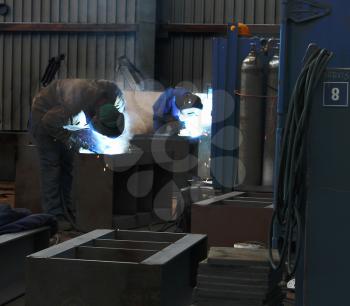 Two welders working in workshop