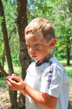 Thoughtful kid in the park holds snails