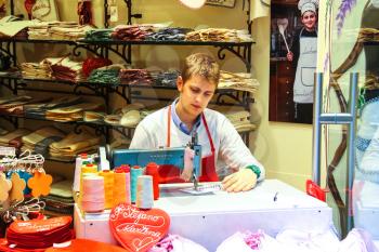 VERONA, ITALY - MAY 7, 2014: Young man works at the sewing machine in the gift shop, Verona Italy
