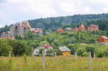 Modern cottages on slopes of forested mountains. Carpathians, Ukraine