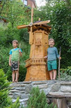Two boys next to small mill in summer city park
