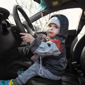 little boy sitting behind the wheel of a car