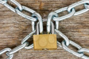 Steel chains and yellow padlock on the wooden background