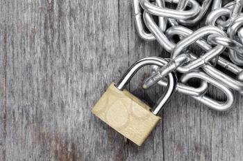 Padlock with chains on the old wooden background