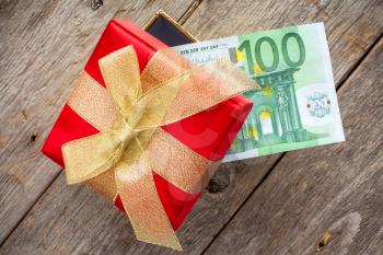 Gift box with one hundred Euro on the wooden background