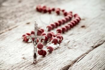 Close-up of catholic rosary on old wooden texture background
