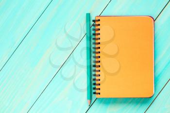  Blank spiral notebook with pencil on the wooden background.Top view.