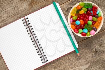 Blank spiral notebook and bowl with mixed candies. Copy-space.