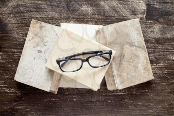 Books and reading glasses on the wooden background.Top view.