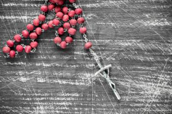 Catholic rosary on the wooden scratched background 