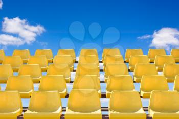 Yellow color sport stadium chair with blue sky background.Conceptual image.