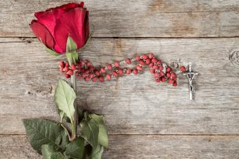 Rosary and old rose on wooden background with copy-space