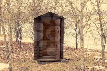 Wooden outdoor toilet with opened door in the park