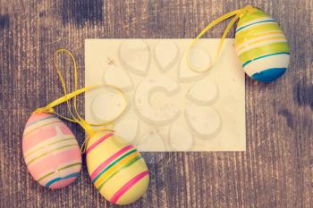 Colorful easter eggs and blank card on wooden background