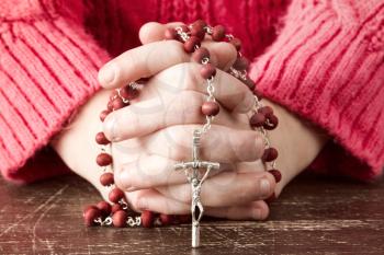Hands of a young Christian child holding  rosary with cross 