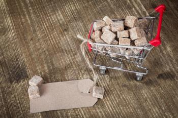 Cane sugar cubes in shopping cart with blank paper tag