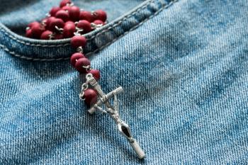 Holy rosary beads in the pocket of the blue jeans