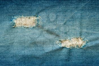 Ripped holes on blue jeans background. Close up blue jeans texture.