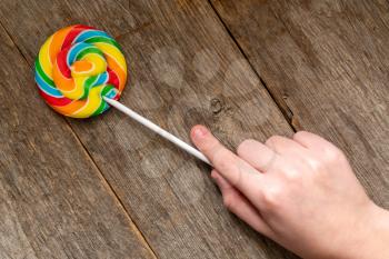 Child's hand taking colorful lollipop. Unhealthy eating concept