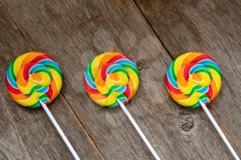 Three colorful lolipops on old wooden background